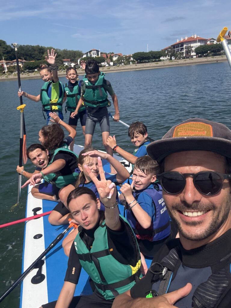 Groupe d'enfants souriants sur un Big Paddle XXL dans la baie de Txingudi à Hendaye